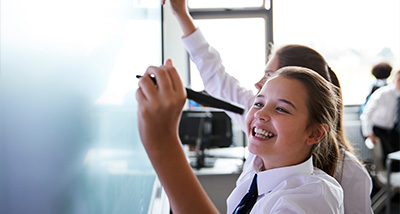 two secondary school pupils writing on an interactive whiteboard